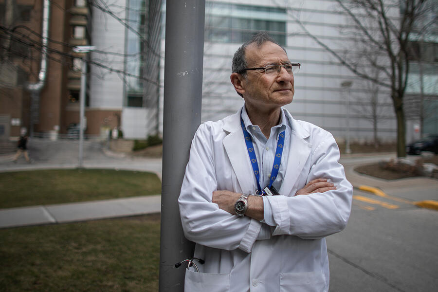 Photograph of Professor Joe Fisher in a lab coat with his arms crossed, smiling a bit